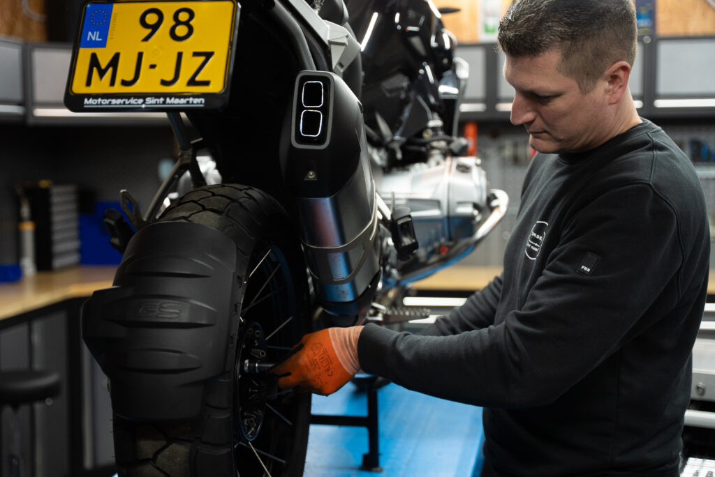 Eigenaar van Motorservice Sint Maarten aan het werk aan een motor.